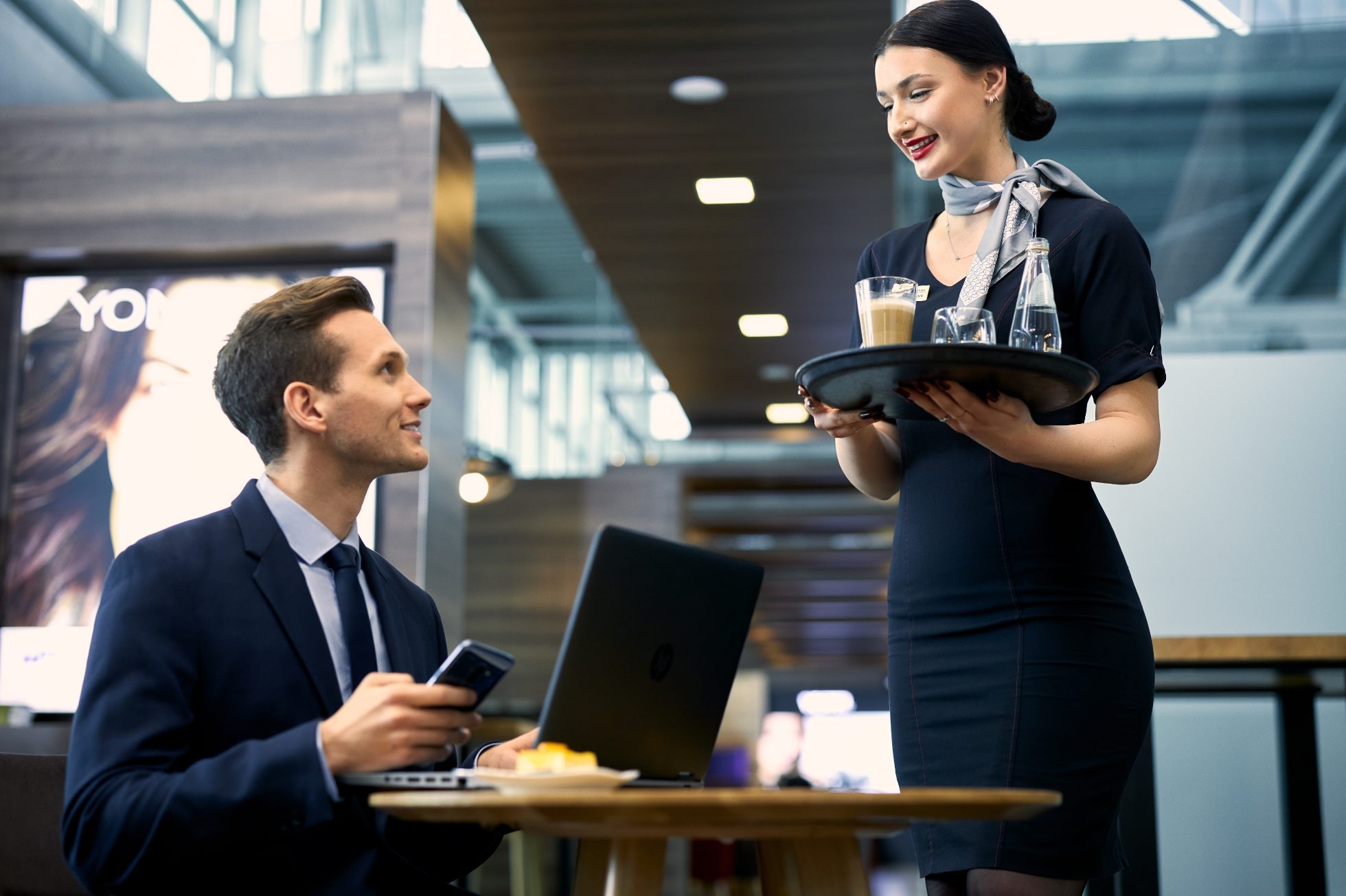 Waitress in restaurant area serving coffee to man working at table